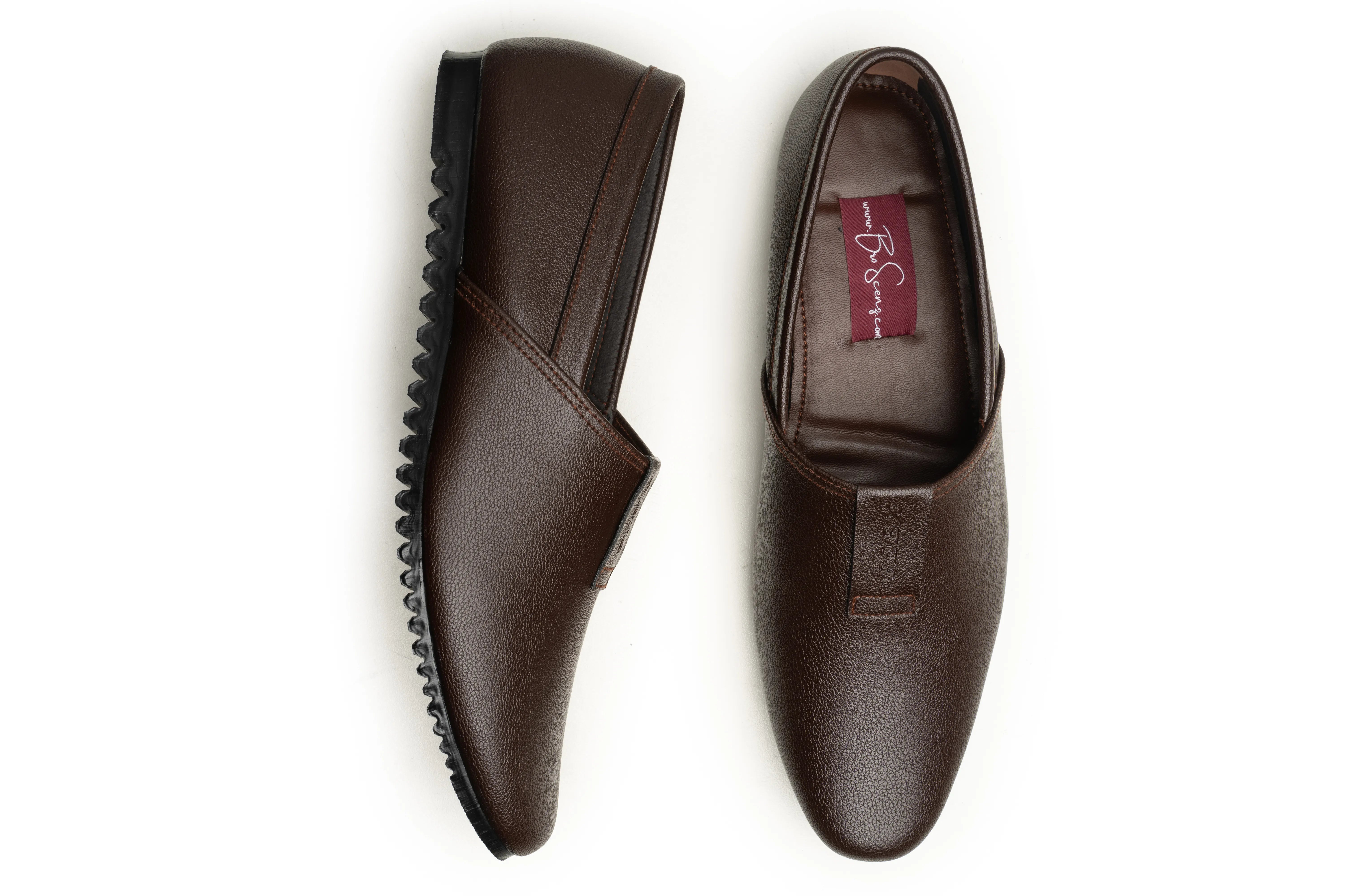 A pair of dark brown leather slip-on loafers shown from the top and side on a plain white background. One shoe displays the textured black sole, and the other shows the interior with a red brand label.