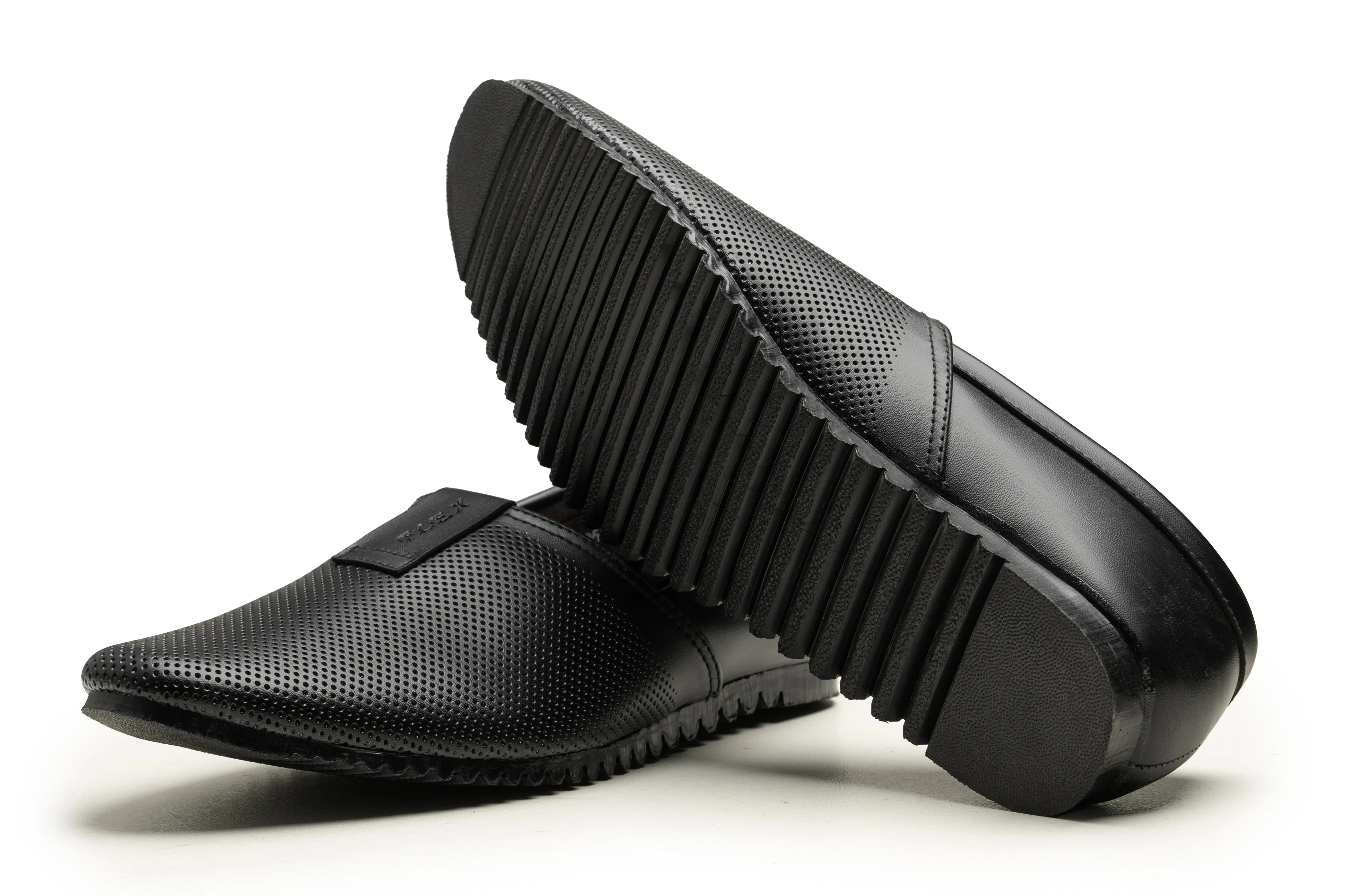 A pair of black slip-on loafers with perforated upper panels, shown on a white background with one shoe standing upright to display the treaded sole and the other lying flat to show the side profile.
