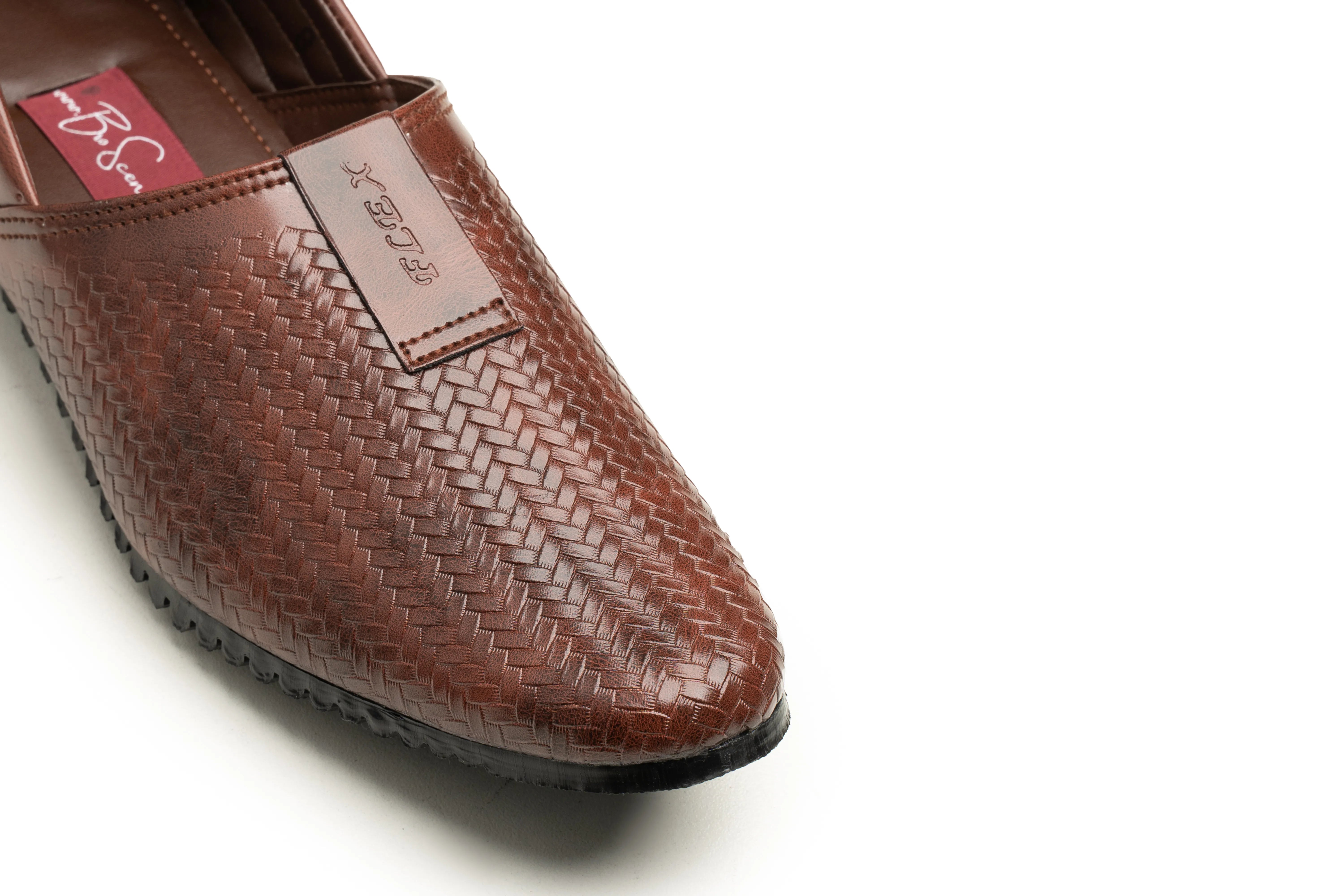 A close-up of a brown woven leather slip-on shoe with a pointed toe, textured basketweave pattern, and a visible 'BFS' brand tag on the side, set against a plain white background.
