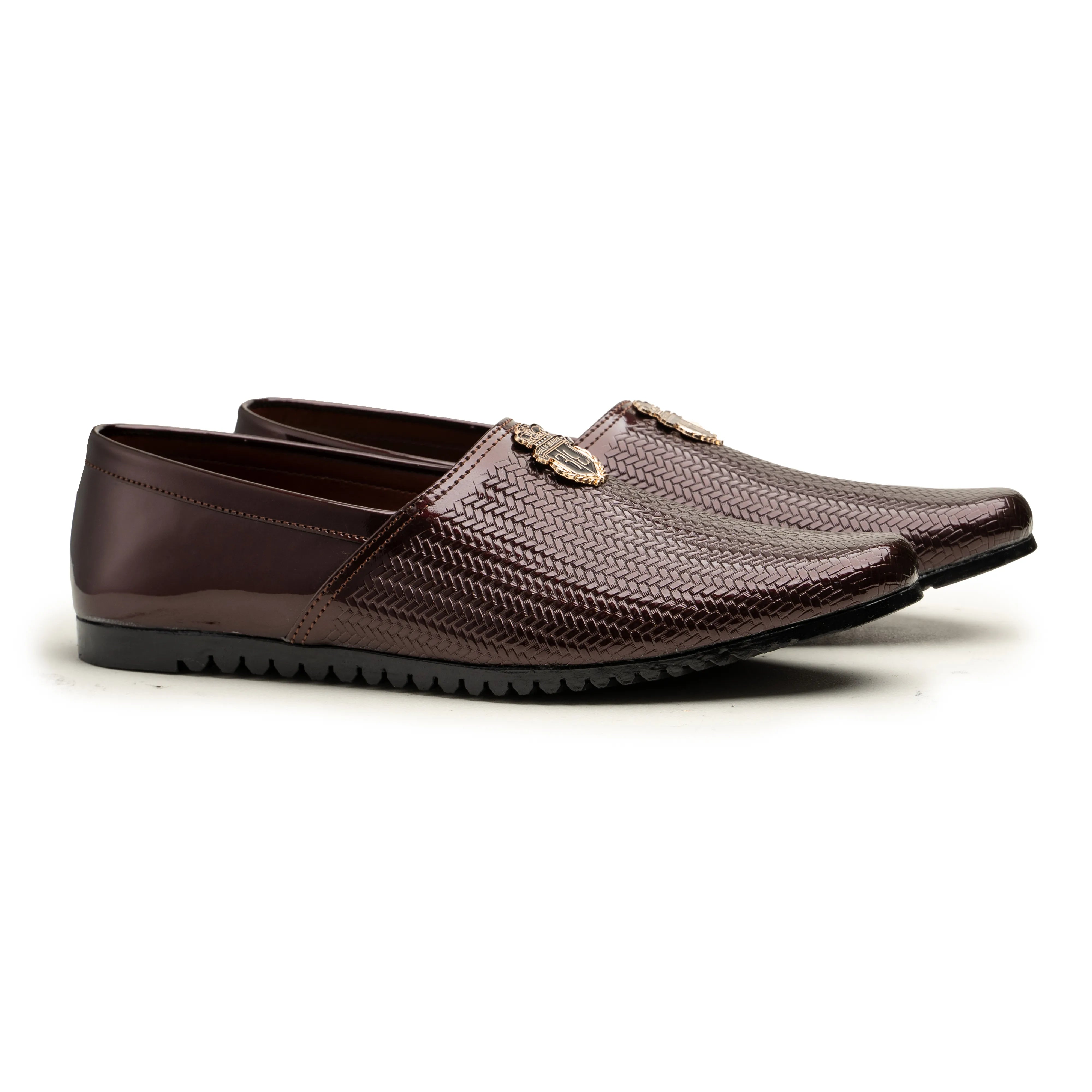 A pair of men's slip-on loafers in a metallic dark brown color, featuring a textured woven pattern on the upper and a small gold-tone decorative emblem on the side, set against a plain white background.