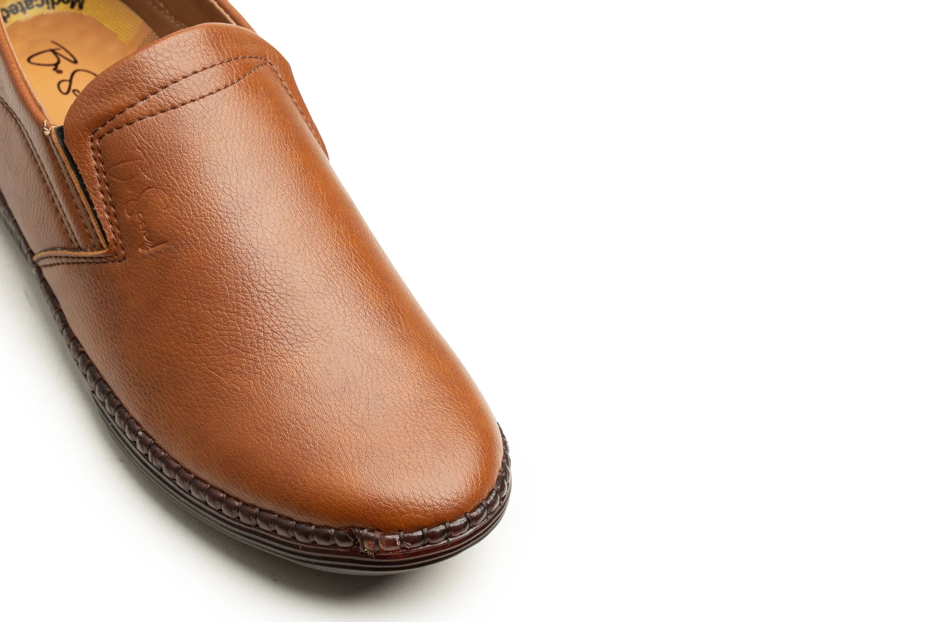 A close-up shot of a brown leather slip-on shoe, showing the toe, side stitching, and textured sole against a plain white background.