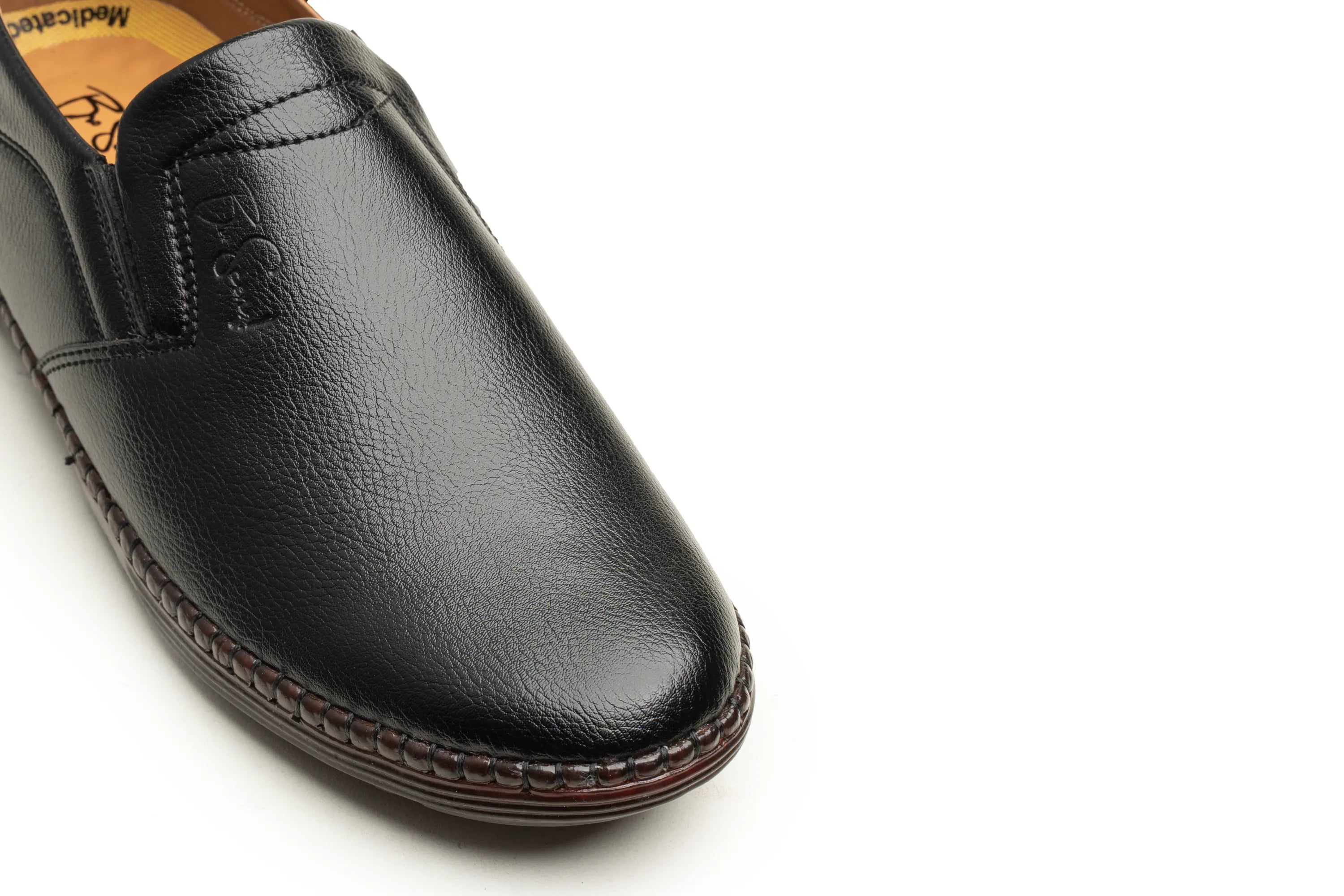 A close-up shot of a black leather slip-on loafer shoe, showing the textured grain, stitched vamp, and dark brown welted sole edge against a plain white background.